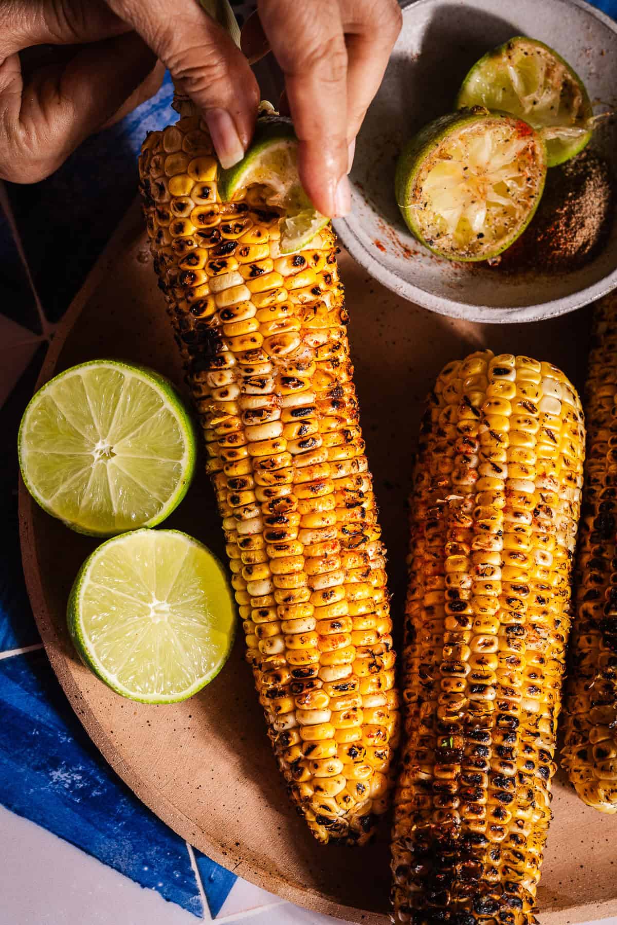 Rubbing a masala covered lime wedge on grilled corn.