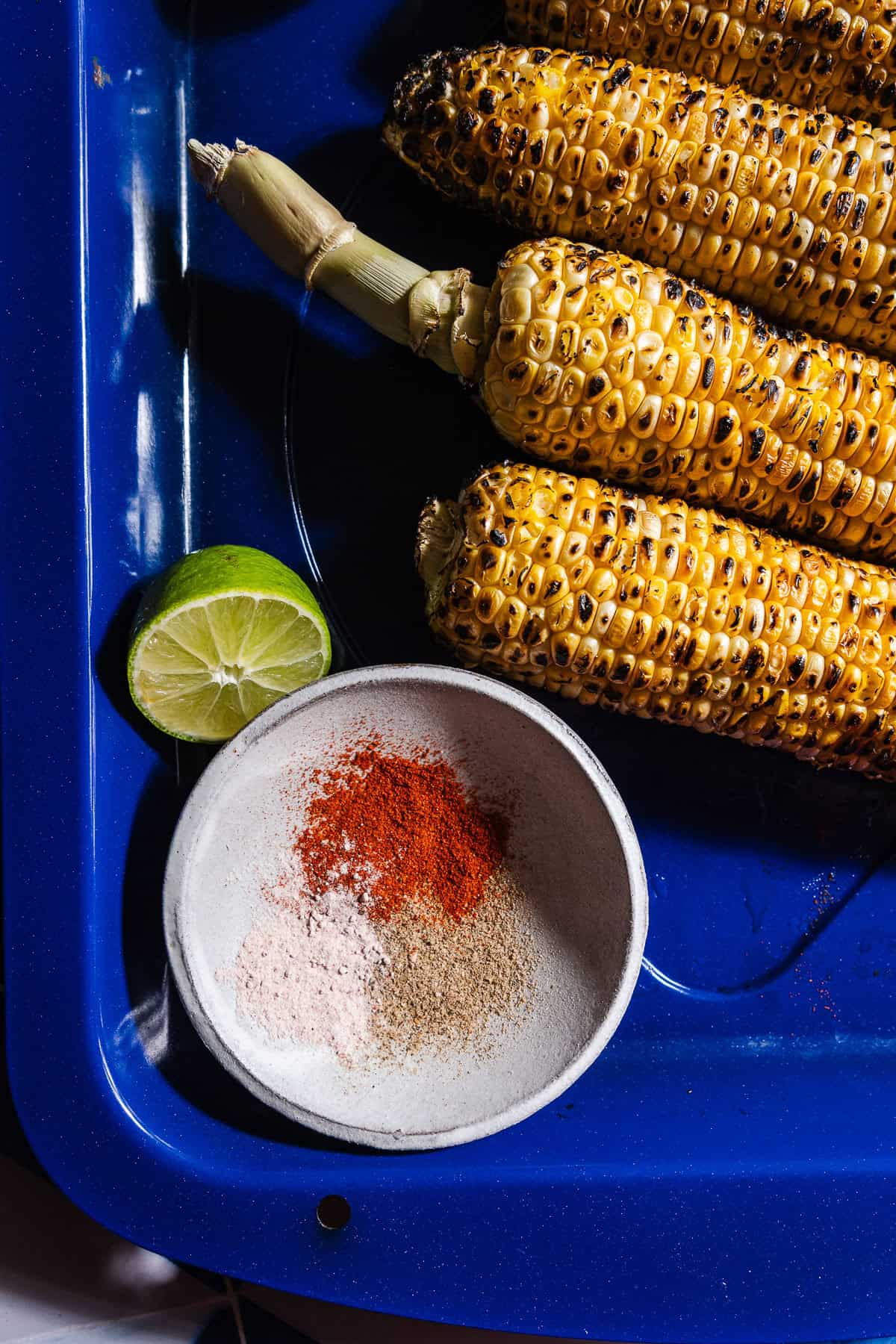 Masalas in a small bowl with lime wedges for rubbing on grilled corn.