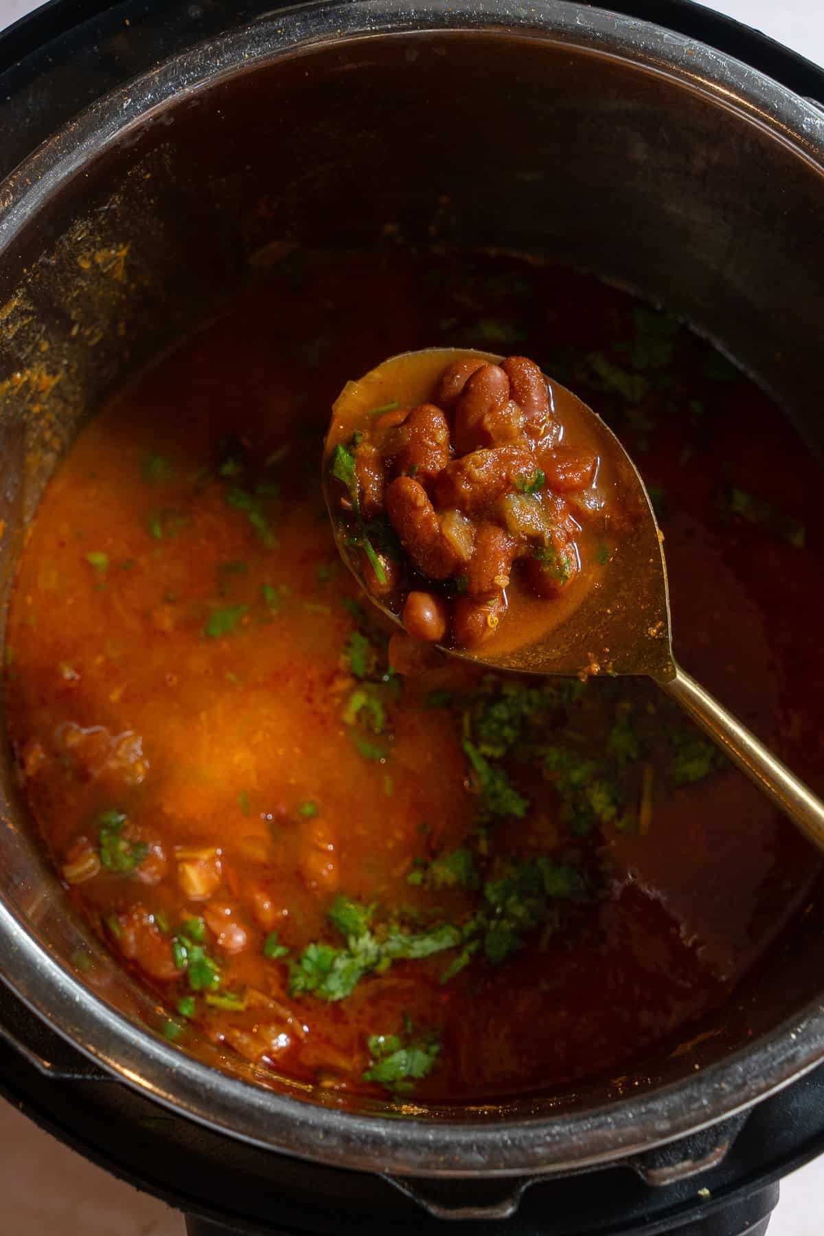 Serving spoon picking up rajma from the Instant Pot.