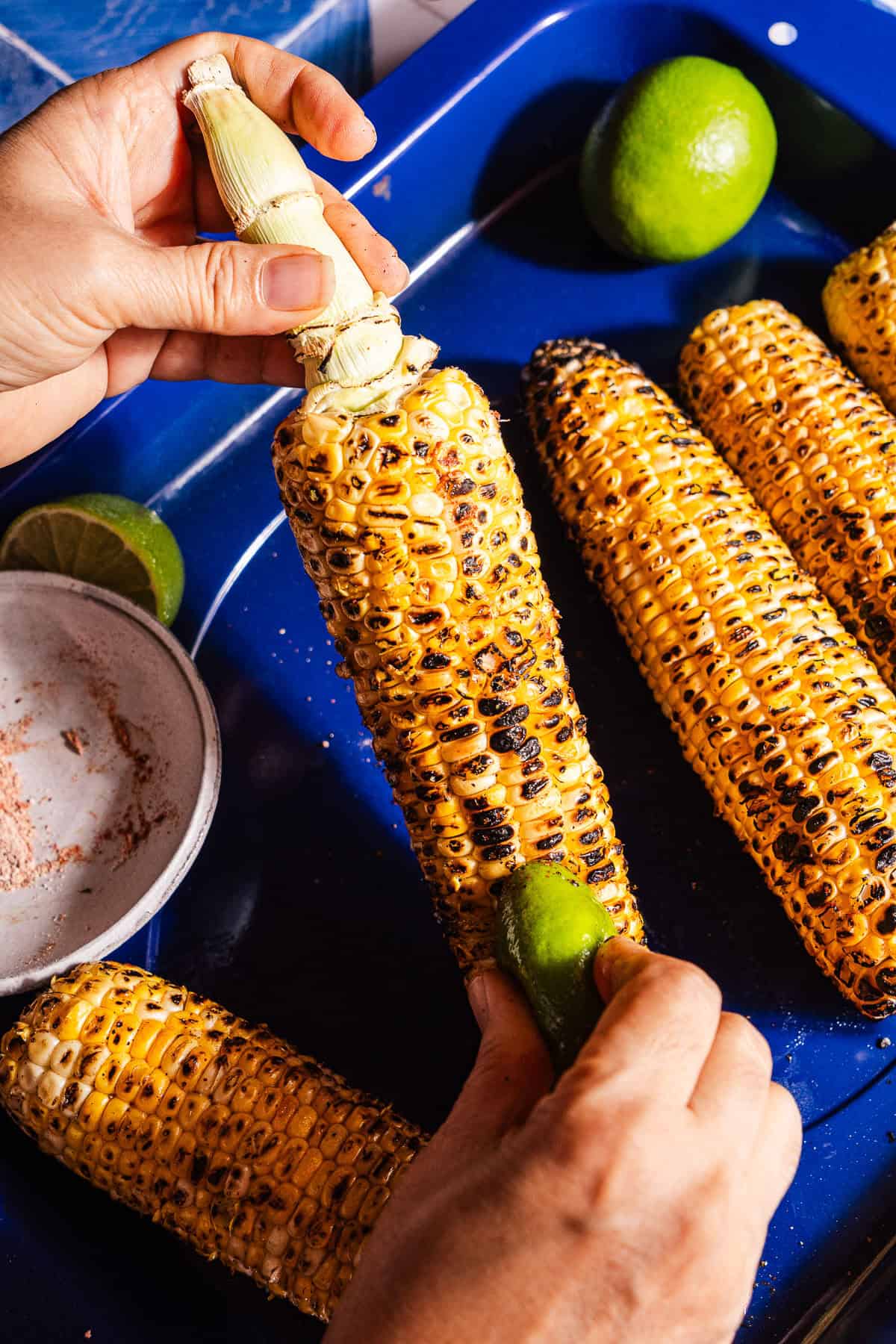 Rubbing a masala covered lime wedge on grilled corn.