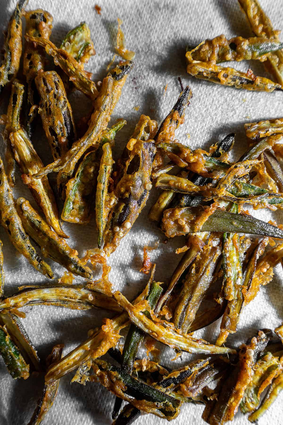Deep fried bhindi draining on a paper towel.