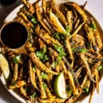 Kukuri bhindi served in a plate with chutney and lime wedges.