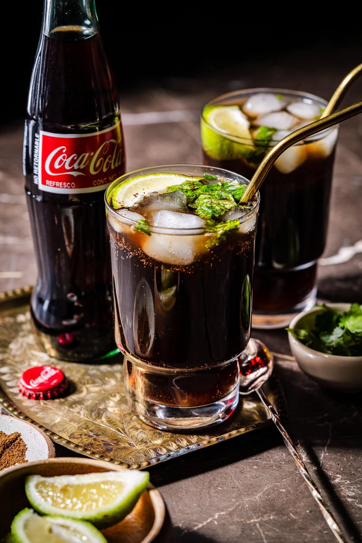 Two glasses of masala coke served with a coke bottle.