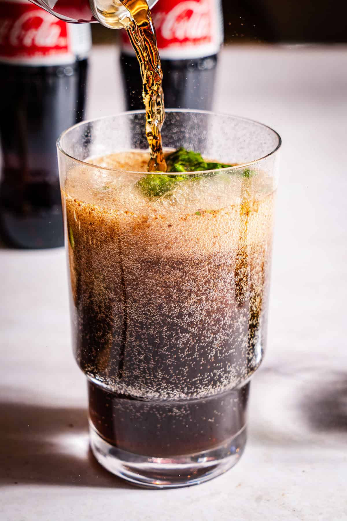 Pouring coke over masala and lime muddled mixture.
