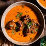Lauki Kofta curry in bowls garnished with cilantro and diced red onions.