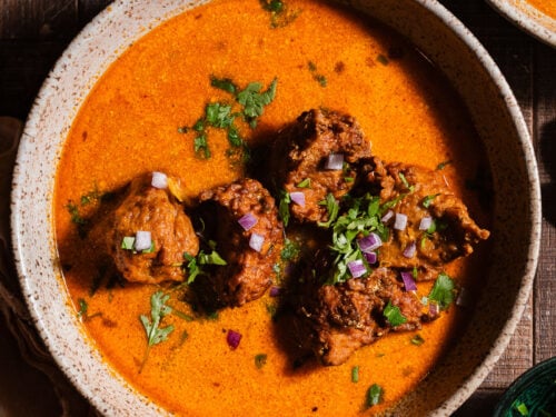 Lauki Kofta curry in bowls garnished with cilantro and diced red onions.