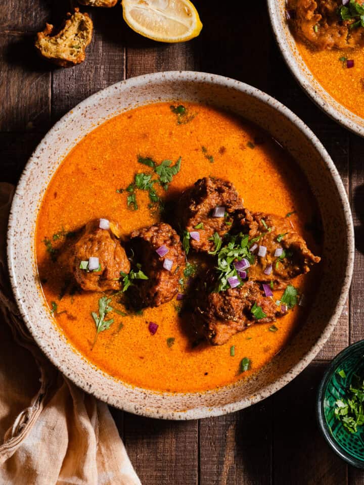 Lauki Kofta curry in bowls garnished with cilantro and diced red onions.
