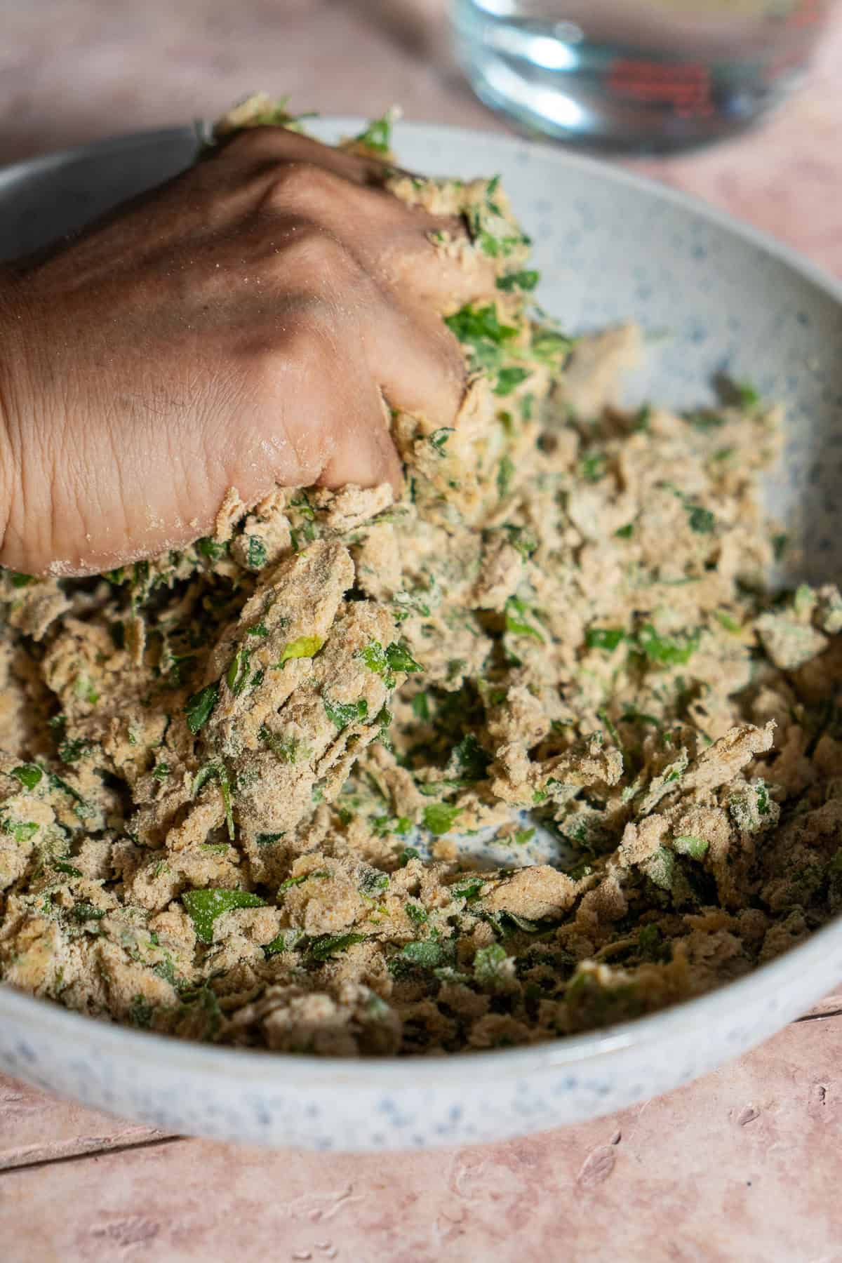 Kneading and combining the methi paratha dough in a bowl.