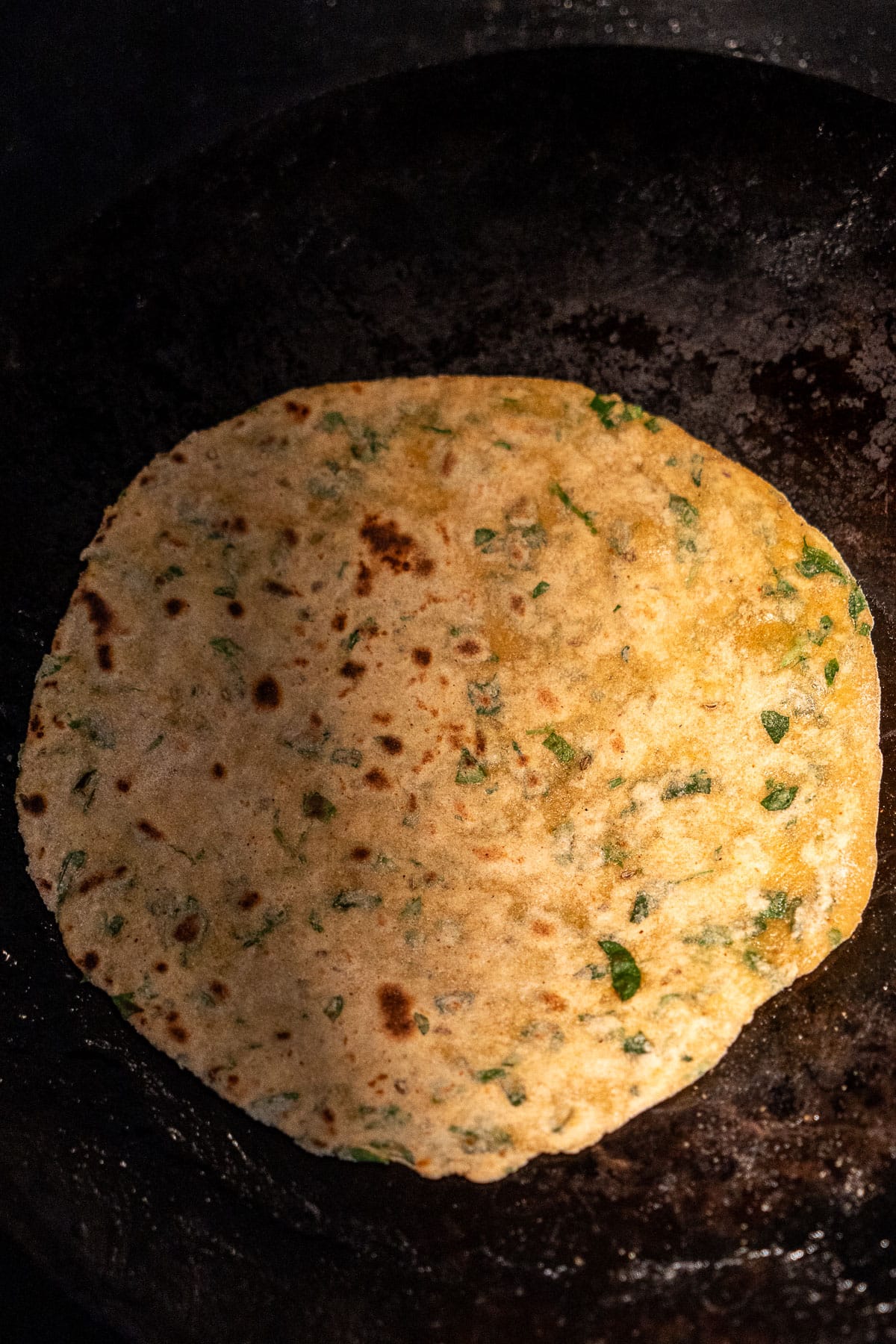 Par cooked methi paratha on a tawa.