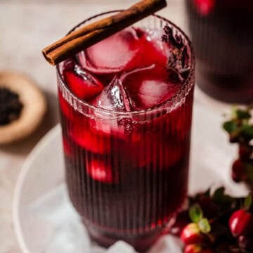 Roselle Hibiscus tea in a glass with a cinnamon stick on top.