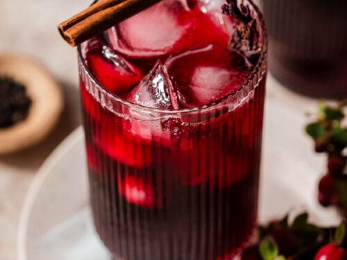 Roselle Hibiscus tea in a glass with a cinnamon stick on top.