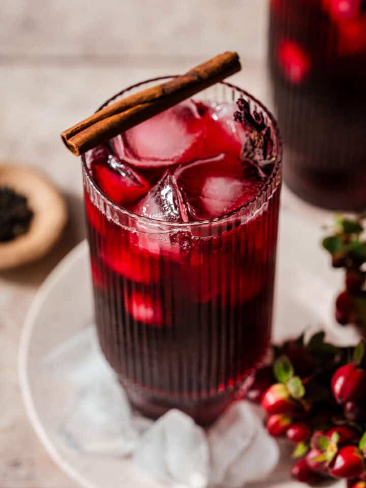Roselle Hibiscus tea in a glass with a cinnamon stick on top.