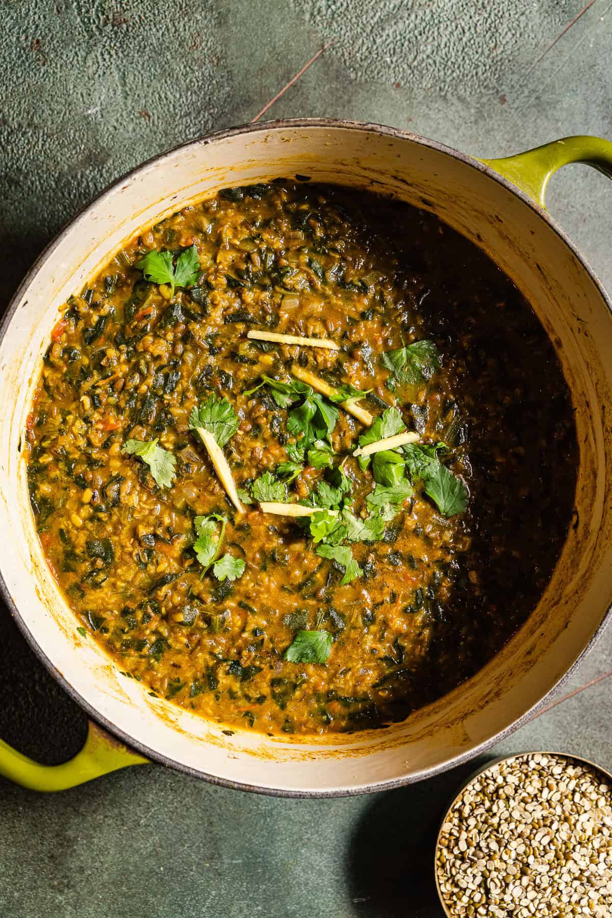 Spinach moong dal garnished with ginger and cilantro in a pot.