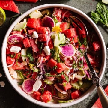 Watermelon Feta Salad in a bowl with fresh edibles flowers.