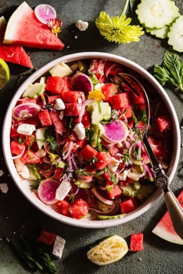 Watermelon Feta Salad in a bowl with fresh edibles flowers.