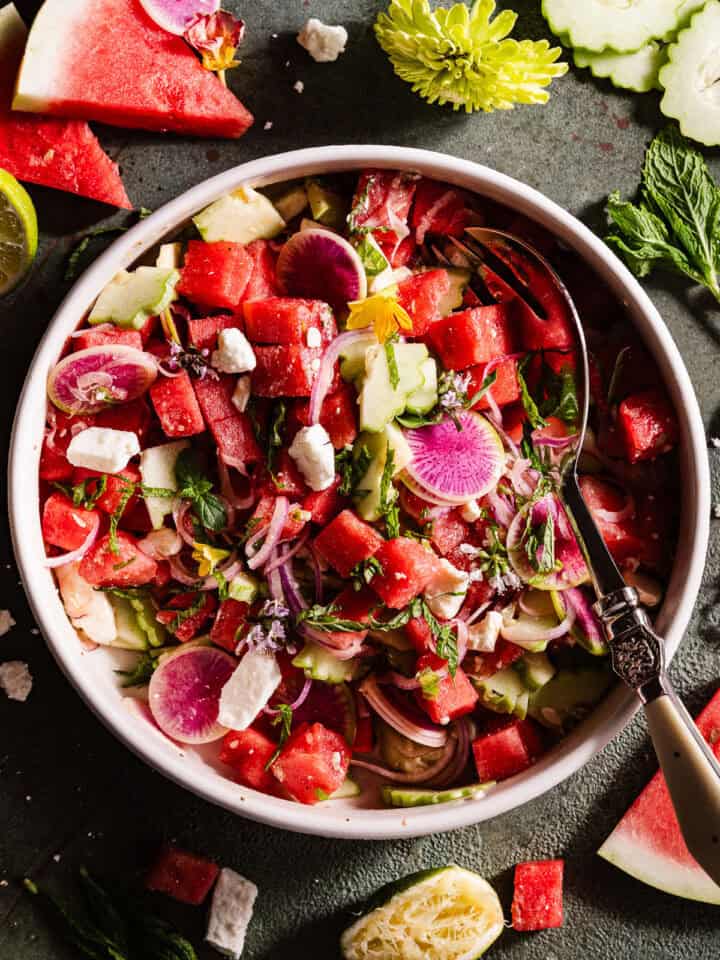 Watermelon Feta Salad in a bowl with fresh edibles flowers.