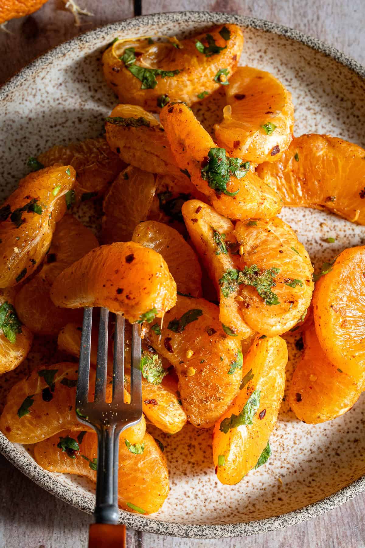 Orange chaat in a plate with a fork.