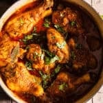 Cooked chicken curry in a dutch oven served with rice and chili peppers.