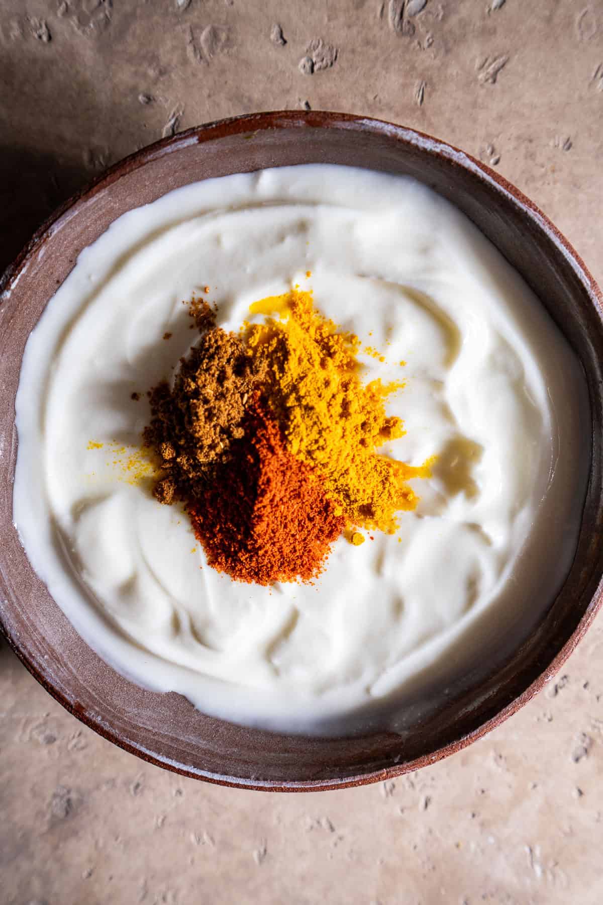 Yogurt in a bowl with unmixed spices.