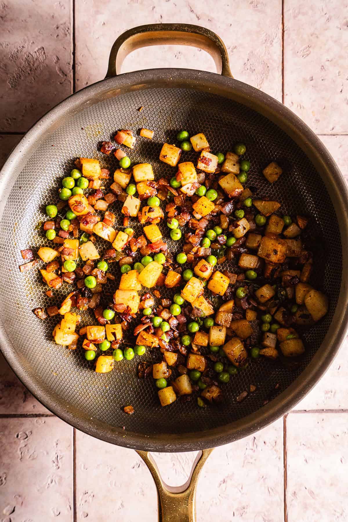Stir-fried spiced vegetables with peas and potatoes in a skillet.