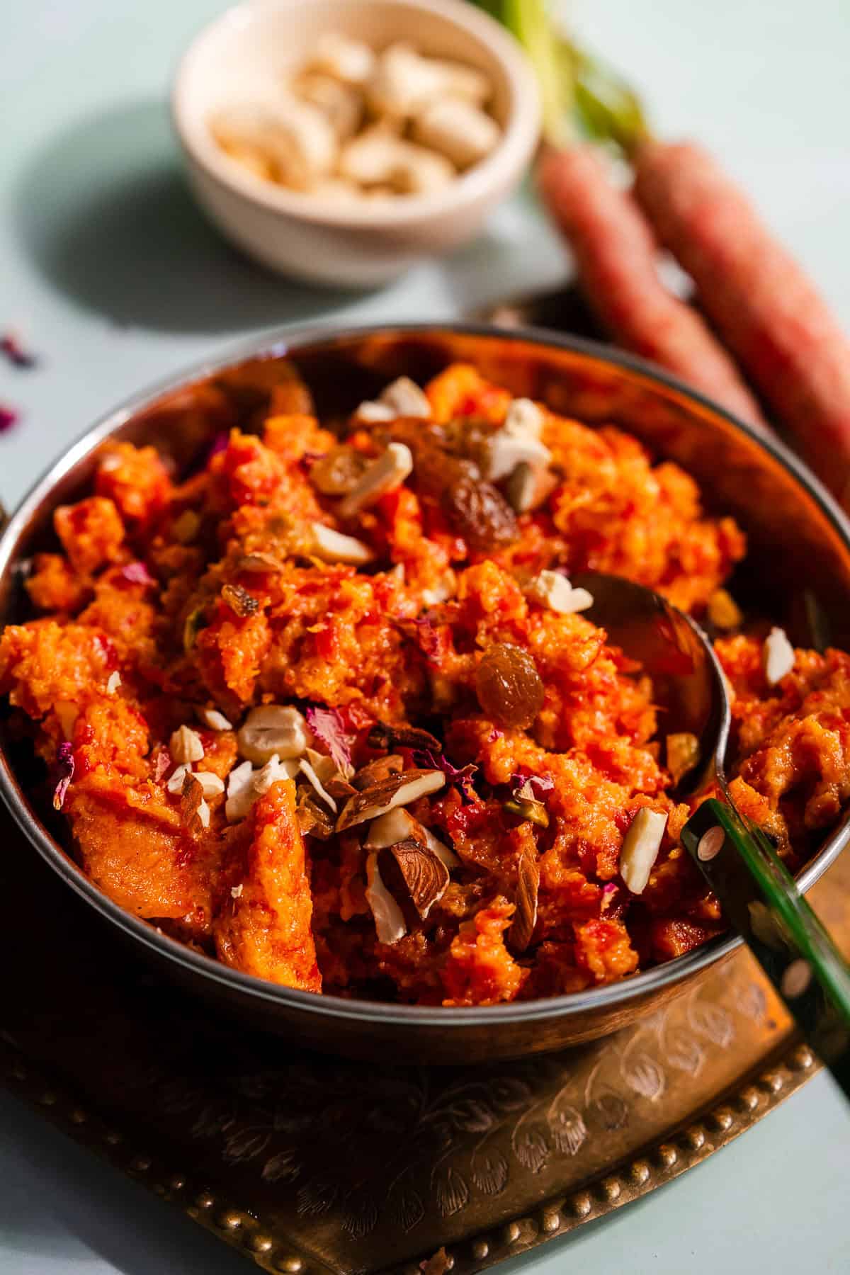 Gajar ka halwa in an Indian kadhai serving bowl served with nuts.