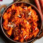 Gajar ka halwa in an Indian kadhai serving bowl served with nuts.