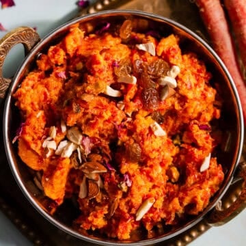 Gajar ka halwa in an Indian kadhai serving bowl served with nuts.