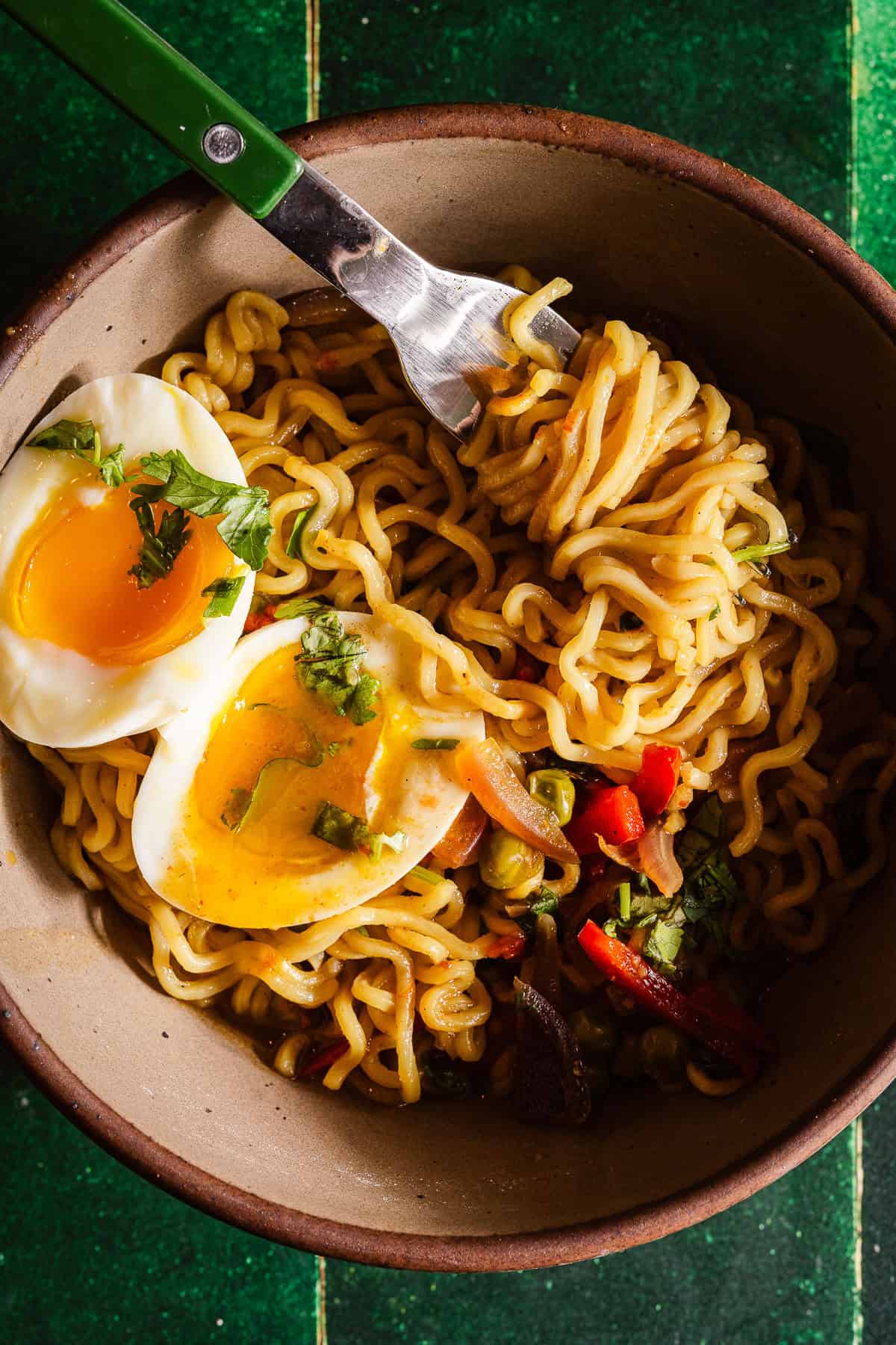 Spicy masala noodles topped with a soft-boiled egg, fresh herbs, and vegetables in a rustic bowl.