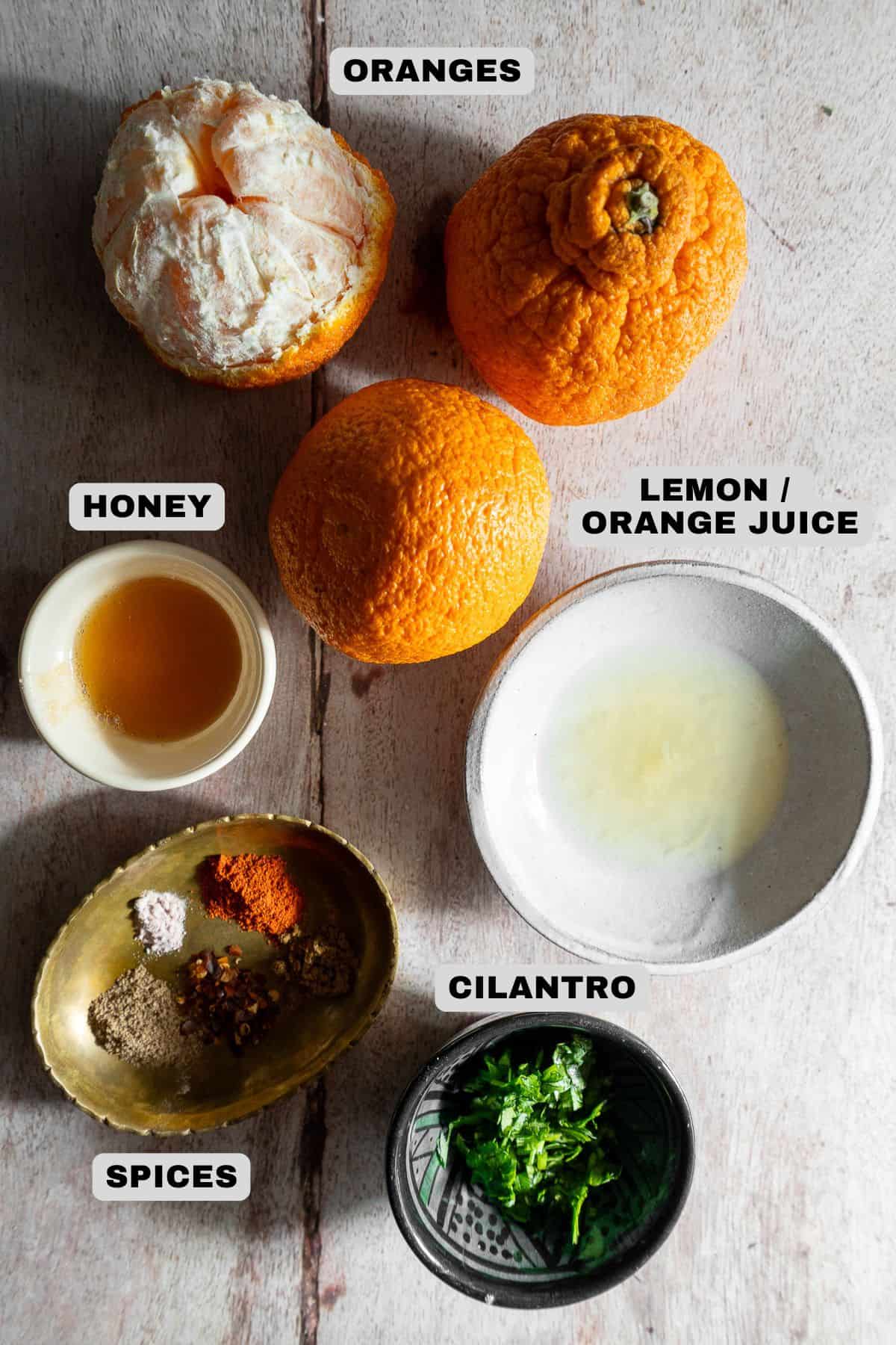 Oranges, honey, lemon/orange juice, spices, cilantro ingredients with labels.