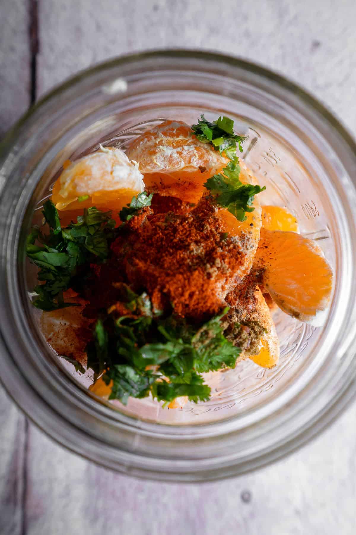 Peeled mandarin orange in a jar with spices and cilantro.