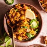 Flavorful vegetable poha with spices, lemon, jalapeno slice, and fresh herbs.