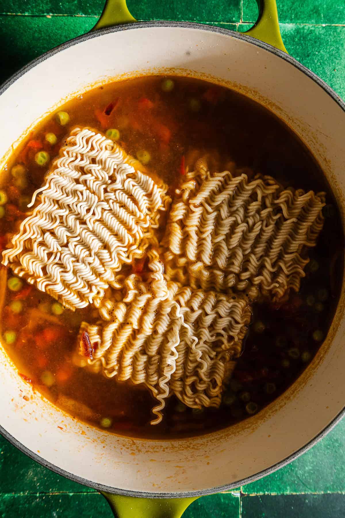 Raw instant noodles in a pot with spiced masala veggie water.