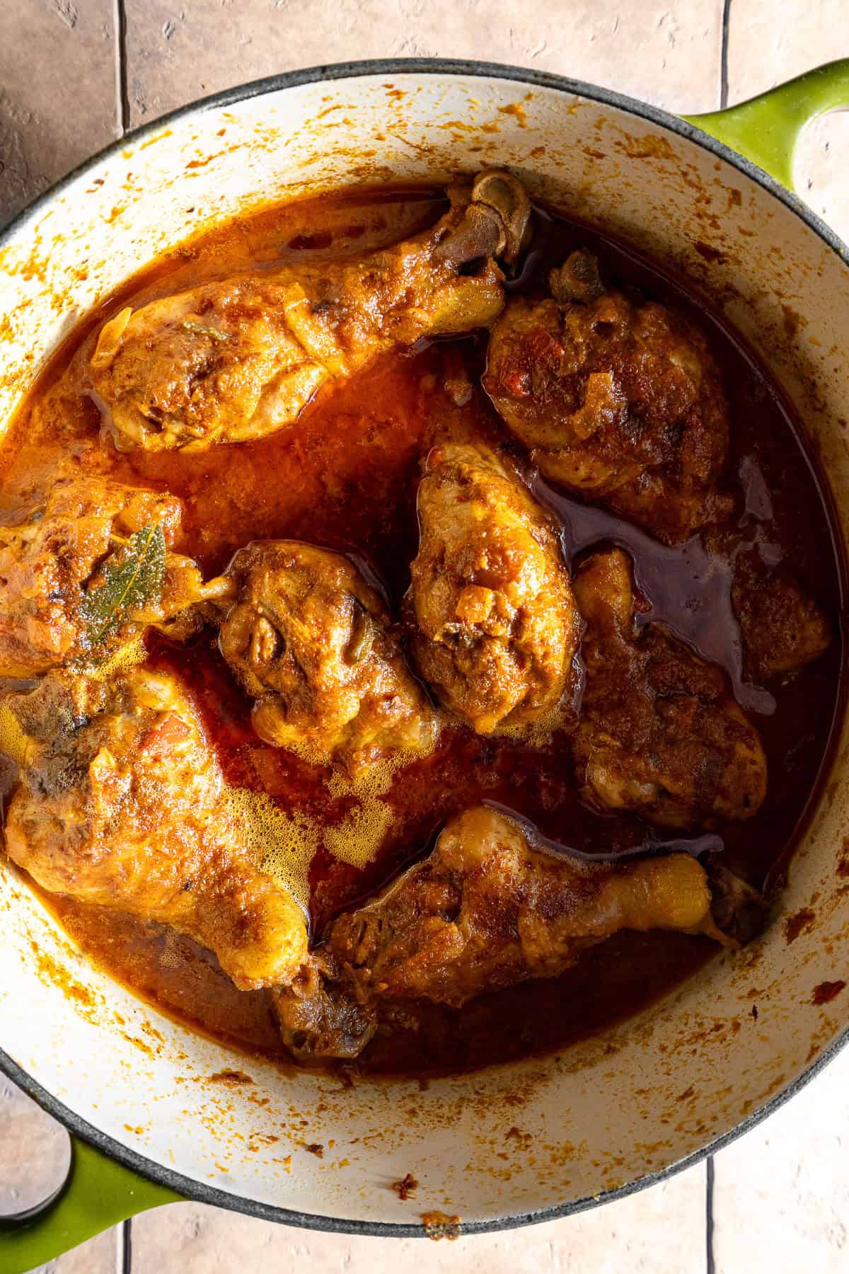 Cooked chicken curry with ghee at the top in a dutch oven.