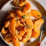 Orange chaat in a plate with a fork.