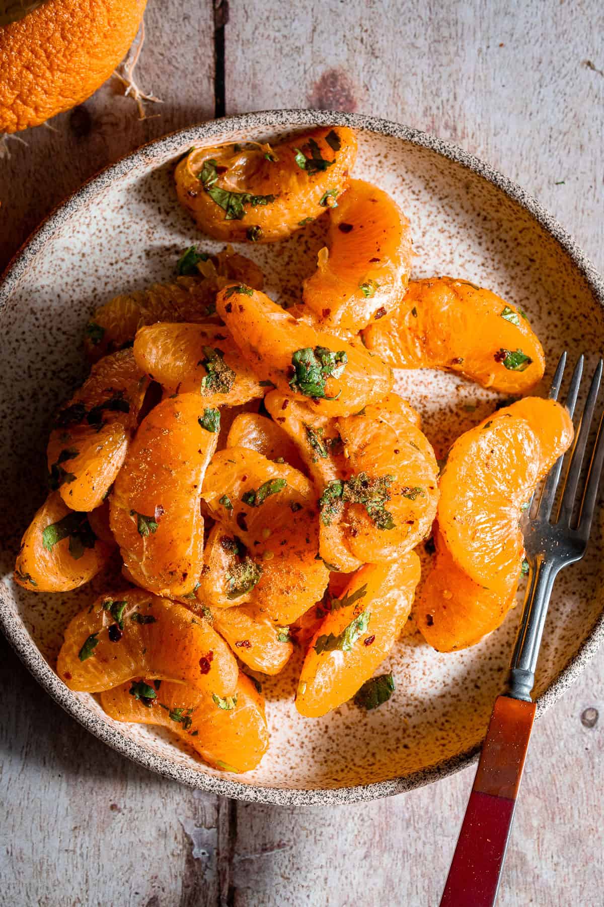 Orange chaat in a plate with a fork.